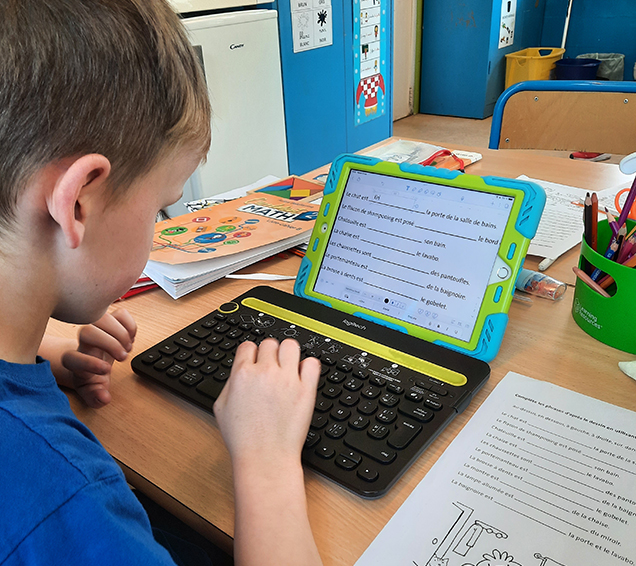 Un jeune utilise un iPad pour écrire une dictée