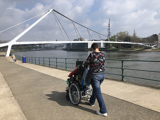 Une référence et une jeune en chaise roulante se baladent le long du parc de la Boverie à Liège. 