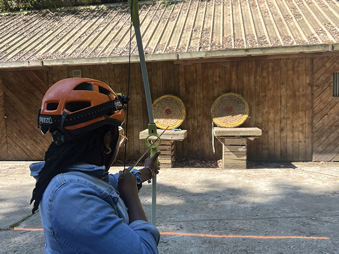 Une Jeune s'apprête à tirer à l'arc à flèche.